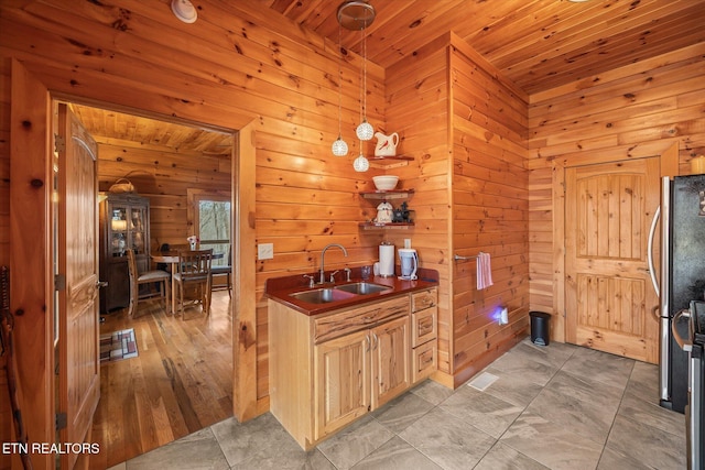 kitchen with a sink, dark countertops, freestanding refrigerator, wood ceiling, and hanging light fixtures