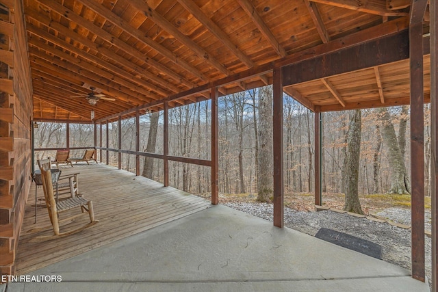 unfurnished sunroom with a view of trees and ceiling fan