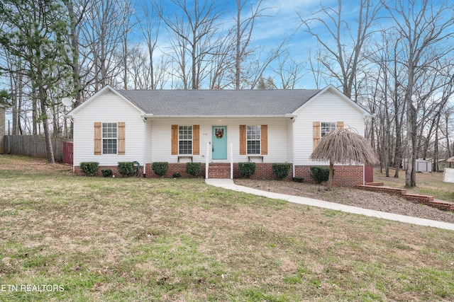 ranch-style home with a porch, a shingled roof, a front lawn, and fence