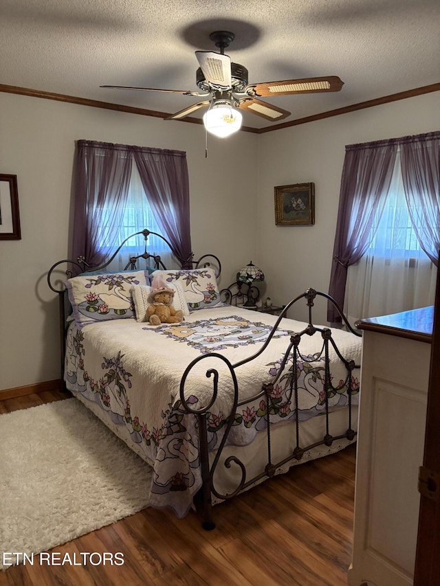 bedroom featuring ornamental molding, a textured ceiling, ceiling fan, and wood finished floors