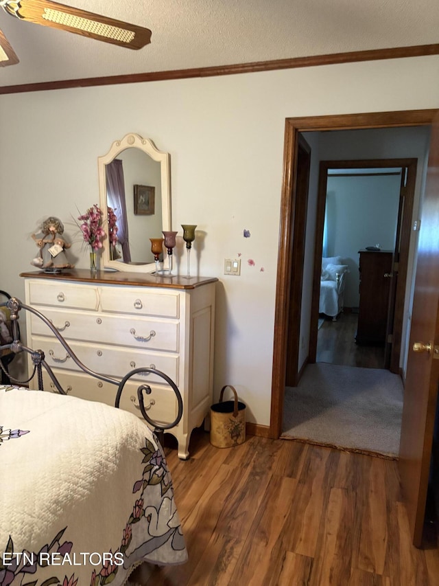 bedroom with ornamental molding, a textured ceiling, ceiling fan, and wood finished floors