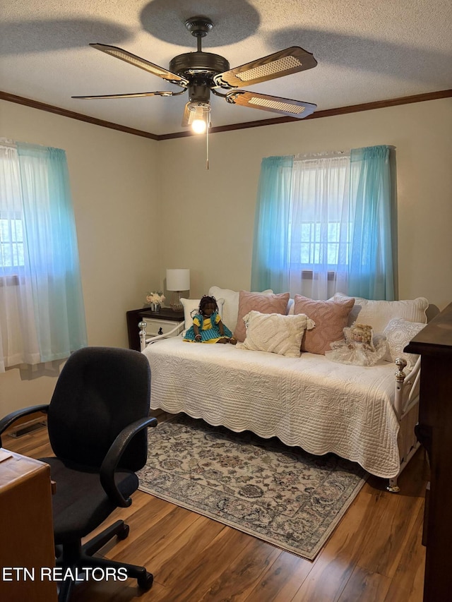 bedroom with a textured ceiling, wood finished floors, ceiling fan, and ornamental molding