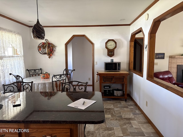 dining room with stone finish floor, crown molding, and baseboards