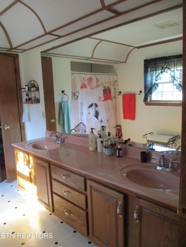 full bathroom with a sink, double vanity, and tile patterned floors