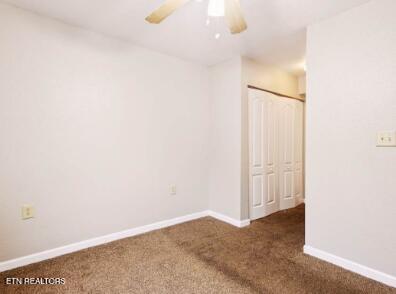 carpeted empty room featuring baseboards and a ceiling fan