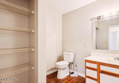 bathroom with toilet, vanity, baseboards, and wood finished floors