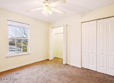 unfurnished bedroom with baseboards, carpet, ceiling fan, and multiple closets