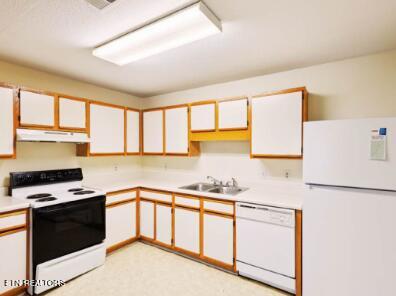 kitchen with under cabinet range hood, a sink, white appliances, white cabinets, and light countertops