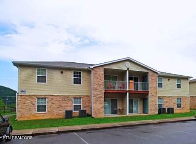 view of building exterior with central AC unit and uncovered parking