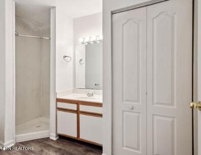 full bath with walk in shower, wood finished floors, and vanity