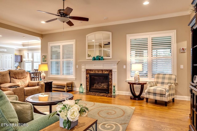 living room with a high end fireplace, crown molding, baseboards, and wood finished floors