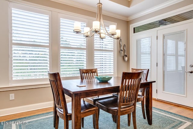 dining space with light wood-style flooring, baseboards, an inviting chandelier, and ornamental molding