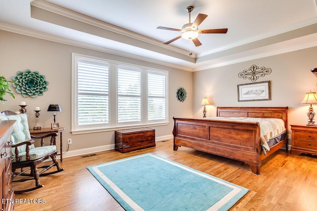 bedroom featuring light wood finished floors, visible vents, crown molding, baseboards, and a tray ceiling