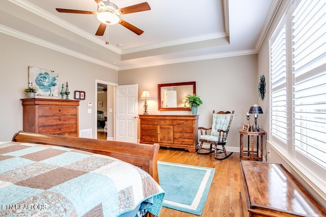 bedroom with crown molding, light wood-type flooring, a raised ceiling, and baseboards