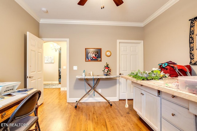 office area with a ceiling fan, baseboards, arched walkways, ornamental molding, and light wood-style floors