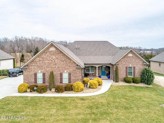 view of front of home featuring brick siding, concrete driveway, a front lawn, and a shingled roof