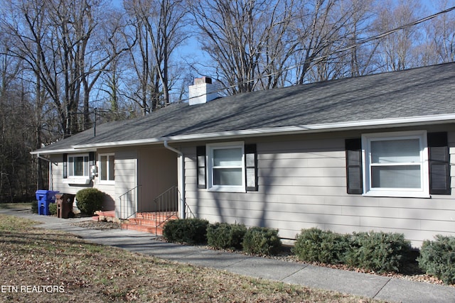 view of front of home featuring a chimney and a shingled roof