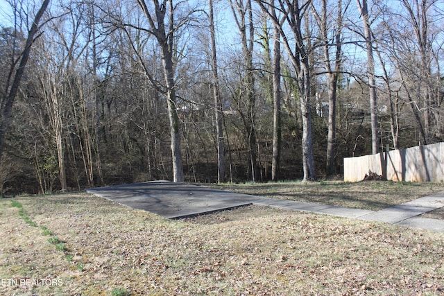 view of yard featuring a wooded view and fence