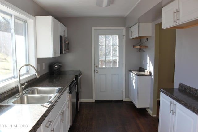 kitchen featuring a sink, stainless steel microwave, range with electric cooktop, and a wealth of natural light