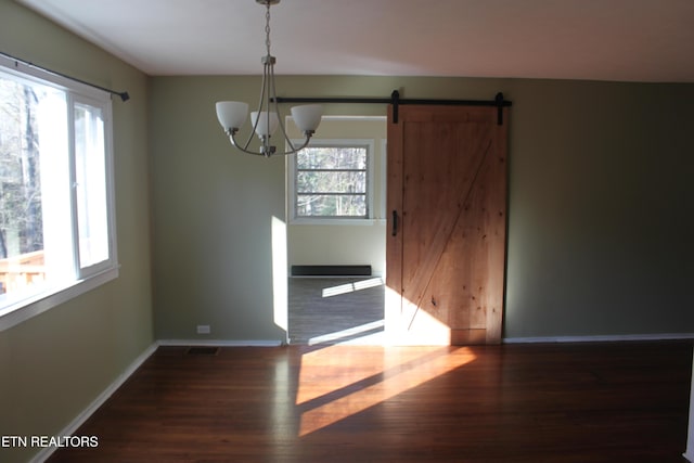 unfurnished dining area with wood finished floors, visible vents, baseboards, a barn door, and a chandelier