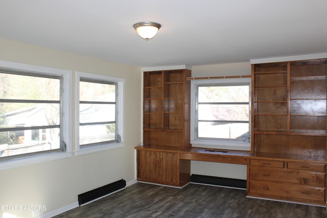 interior space featuring a wealth of natural light, built in desk, dark wood finished floors, and baseboards