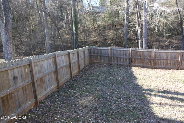 view of yard featuring a fenced backyard and a view of trees