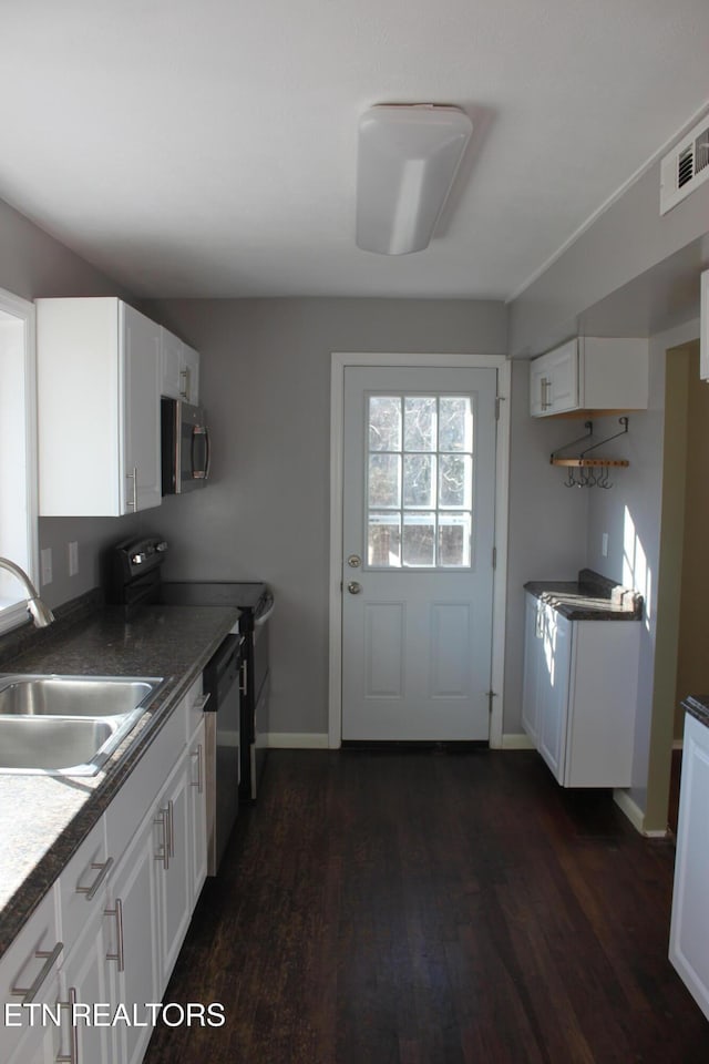 kitchen featuring visible vents, a sink, dark wood-style floors, white cabinetry, and stainless steel appliances