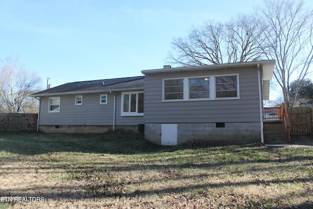 rear view of house featuring a yard, fence, and crawl space