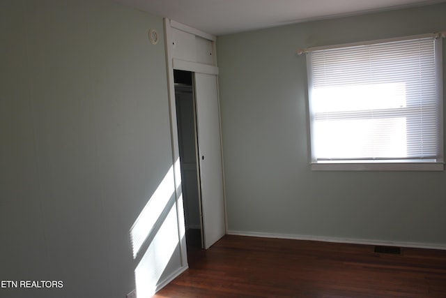 spare room with dark wood-type flooring and baseboards