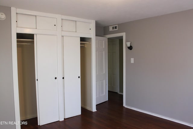 unfurnished bedroom with visible vents, baseboards, and dark wood-style flooring