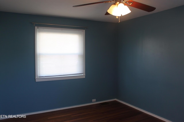 spare room featuring dark wood-style floors, ceiling fan, baseboards, and a wealth of natural light