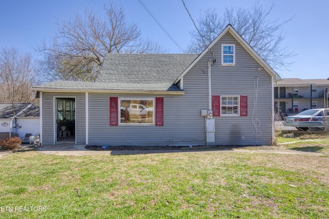 back of property with a yard and roof with shingles