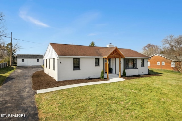 single story home with a front lawn, roof with shingles, a chimney, an outbuilding, and driveway