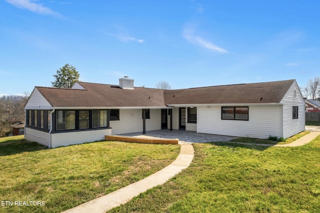 back of house with brick siding, roof with shingles, a chimney, a yard, and a patio