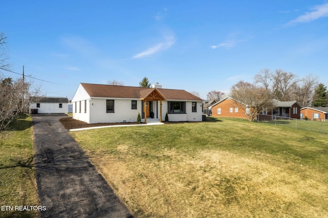 single story home featuring stucco siding, a front lawn, driveway, and fence