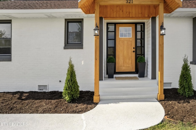 doorway to property featuring crawl space, brick siding, and a shingled roof