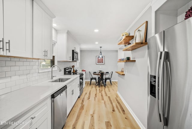 kitchen featuring a sink, light countertops, white cabinets, appliances with stainless steel finishes, and backsplash