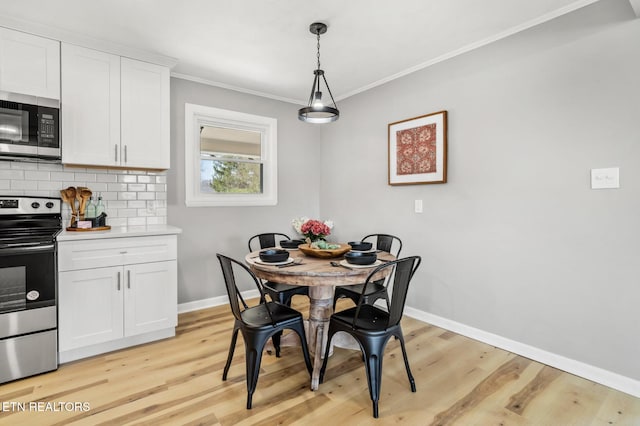 dining space featuring light wood-style flooring, crown molding, and baseboards