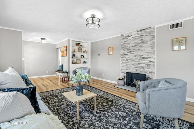 living area with visible vents, crown molding, and wood finished floors