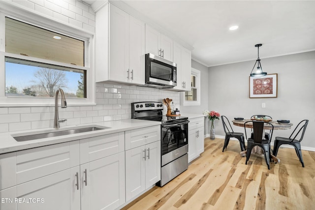 kitchen featuring ornamental molding, decorative backsplash, light countertops, a sink, and appliances with stainless steel finishes