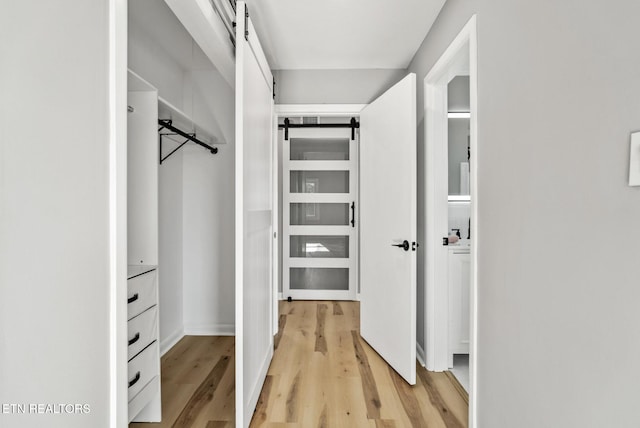 spacious closet with a barn door and light wood finished floors