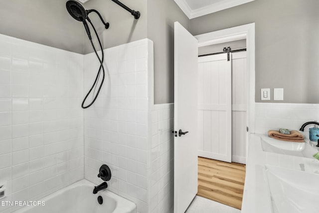 bathroom featuring a wainscoted wall, tub / shower combination, a sink, crown molding, and tile walls