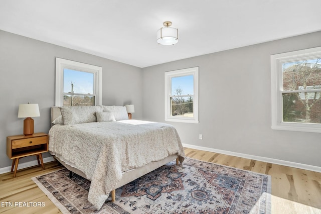 bedroom featuring light wood finished floors, multiple windows, and baseboards