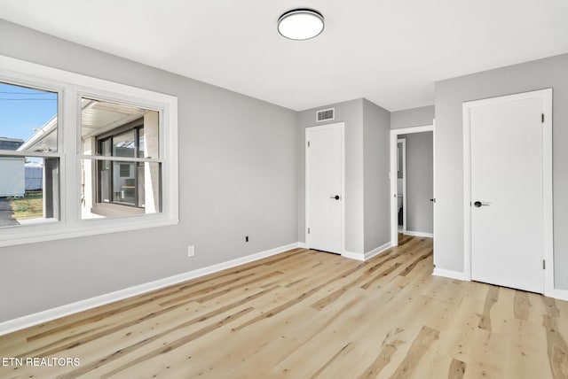 unfurnished bedroom with wood finished floors, baseboards, and visible vents