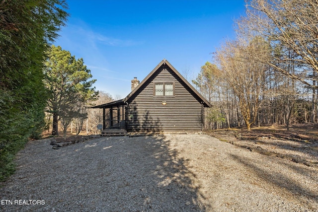 view of side of property with driveway and a chimney