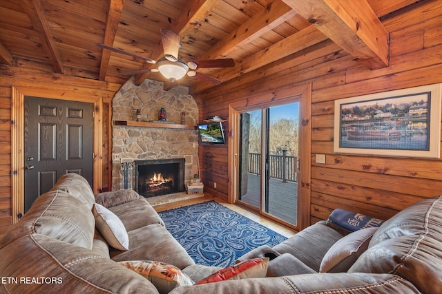 living room with beam ceiling, a stone fireplace, wood walls, and wood ceiling