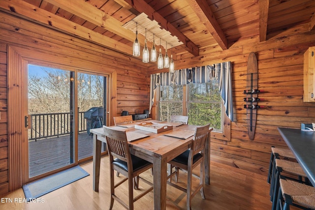 dining area featuring wooden ceiling, wood walls, light wood finished floors, and beam ceiling