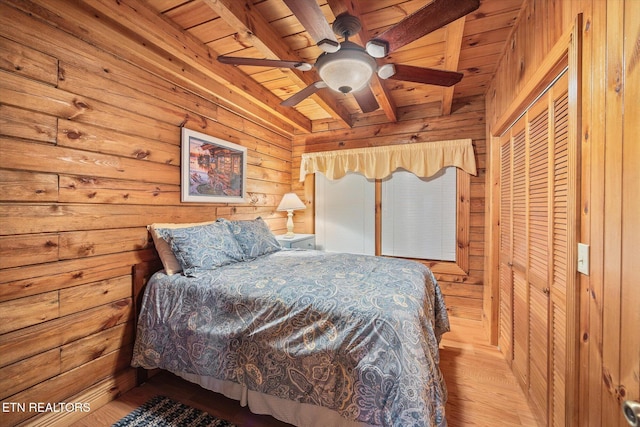 bedroom featuring a closet, wooden walls, wooden ceiling, and a ceiling fan