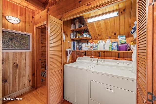 washroom with wood finished floors, wooden walls, and washing machine and dryer