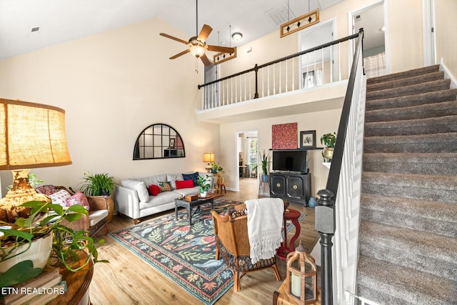 living room featuring stairs, high vaulted ceiling, wood finished floors, and ceiling fan